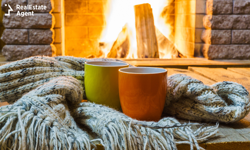 Two mugs wrapped in scarf in front of fireplace