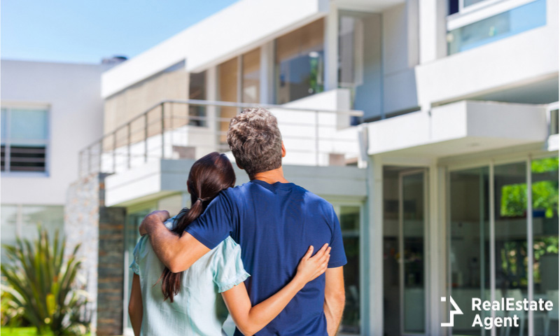 couple embracing in front of new big modern house