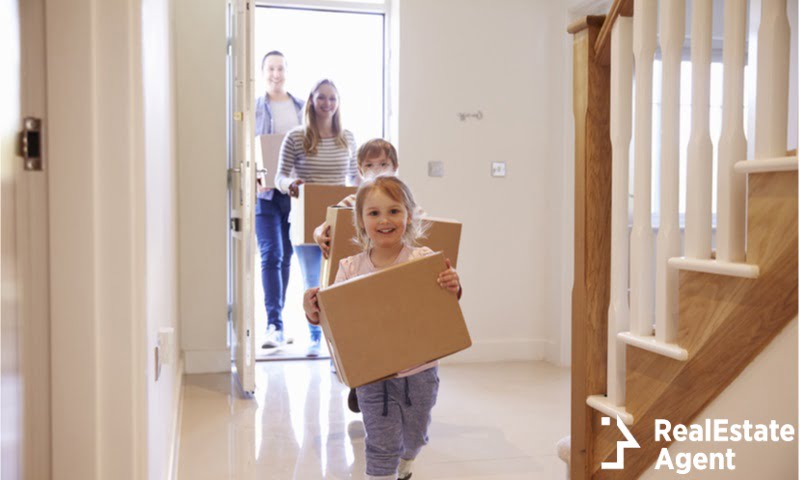 family carrying boxes into new home
