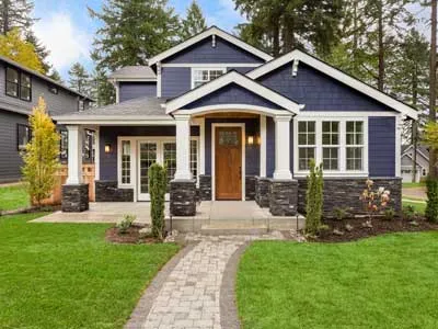 beautiful exterior newly built luxury home with green lawn in front of the house and natural stone