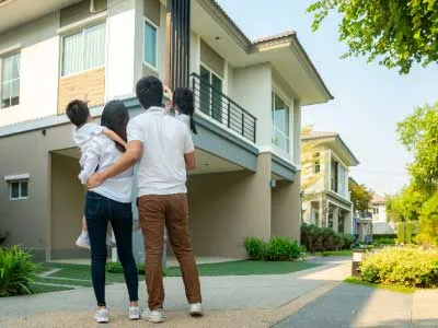 beuaitful family portrait smilling to a house