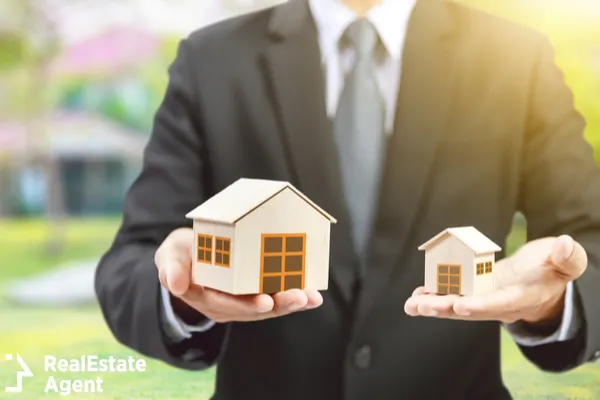 businessman holding small and big house