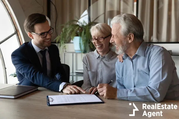 excited senior couple buyers sign paper