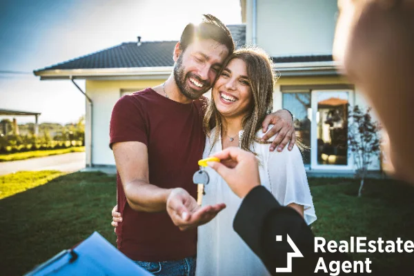happy millenial couple receiving key realtor