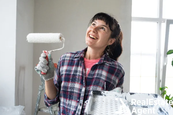 happy young woman paint roller white walls
