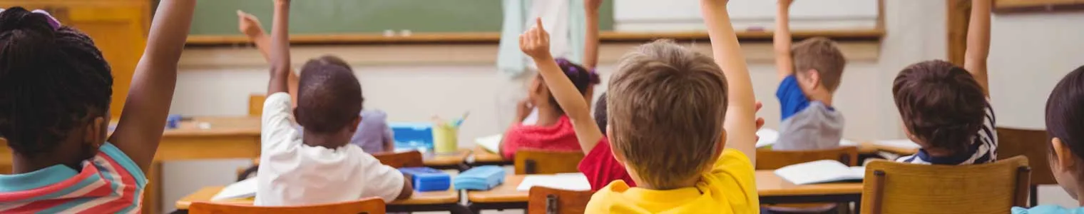 young children in classroom raising hands