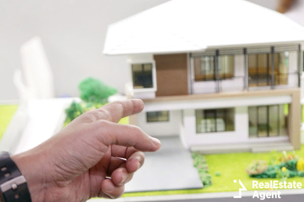 mand hand pointing to house model