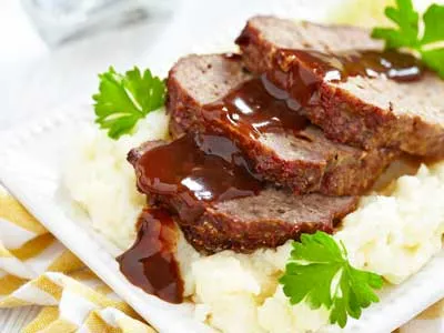 delishious looking meatloaf with brown souce and mashed patatoes on the side