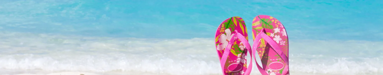 paired colored sandals on white sand