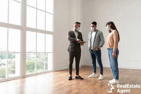 property agent in suit and protective medical maks showing blueprints