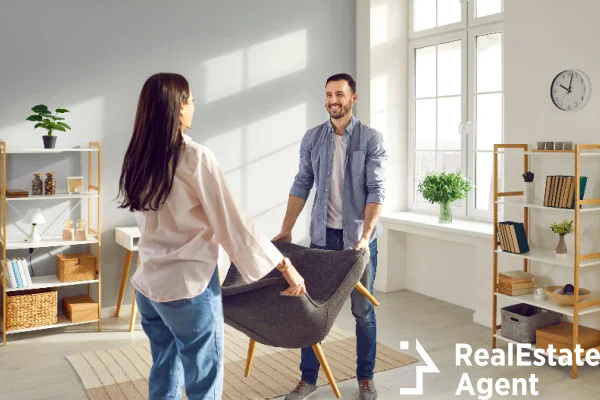 young couple carrying armchair into their