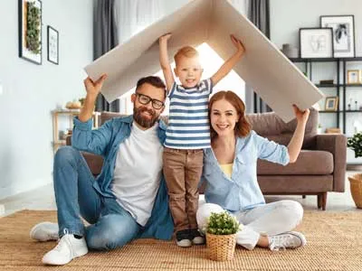 young family, mom, dad and son, holding a board roof over their heads