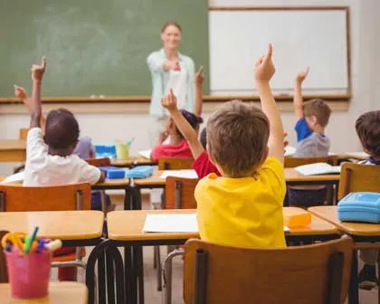 kids in classroom with hands raised